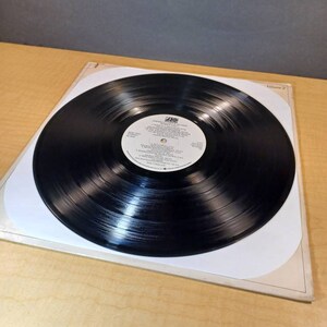 Puede incluir: Disco de vinilo negro con una etiqueta blanca. La etiqueta tiene el texto "SANDALWOOD" y "VOLUME 2" impreso en ella. El disco est&aacute; en una funda interior de papel blanco.