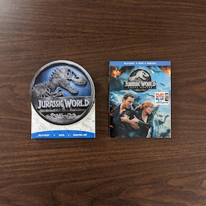 May include: A Jurassic World Fallen Kingdom Blu-ray, DVD, and Digital HD combo pack. The front cover features a close-up of Chris Pratt and Bryce Dallas Howard running from a dinosaur. The back cover features a blue dinosaur with the text "Play with Blue" on a white background.