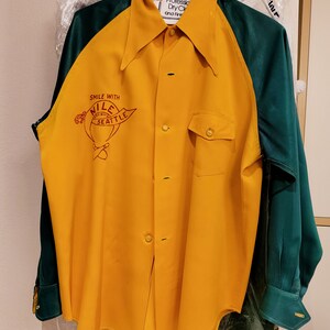 May include: A yellow and green long-sleeved shirt with a red and white logo that says "Smile with Nile" and "Seattle".