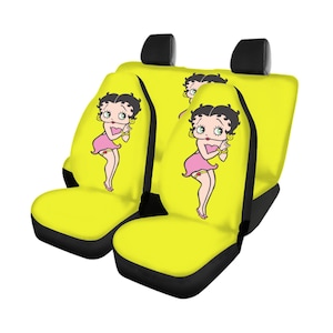 May include: Yellow car seat covers with a cartoon image of Betty Boop in a pink dress. The seat covers have black accents and headrest covers. The Betty Boop image is repeated on the seat covers.