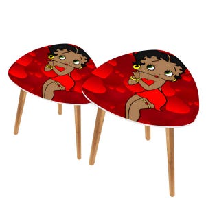 Op de afbeelding: Twee bijzettafels met een cartoonafbeelding van Betty Boop op het tafelblad. De tafels hebben een rode achtergrond met hartvormen en witte randen. De poten zijn van lichtkleurig hout.