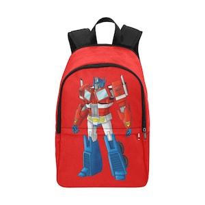 May include: Red backpack with a graphic of Optimus Prime, a robot from the Transformers franchise. The robot is in its robot form and is red, blue, and white.