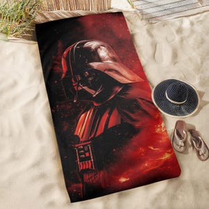Könnte beinhalten: Ein Strandtuch mit einer dunklen Silhouette von Darth Vader vor einem feurigen roten und orangenen Hintergrund.