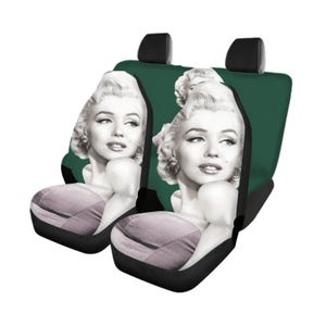 May include: A pair of dark green car seat covers featuring a black and white photographic print of Marilyn Monroe on the backrests. The covers include integrated headrests and a contoured seat base design with a light gray fabric section.