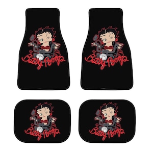 May include: Set of four black car floor mats featuring a Betty Boop design. The mats have a cartoon image of Betty Boop on a motorcycle, with the words "Betty Boop" in red script. The mats are designed for car interiors.