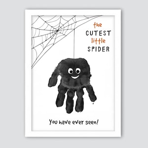 Pode incluir: Uma impressão emoldurada com um desenho de aranha de impressão manual. A aranha preta tem um rosto sorridente e está suspensa em uma teia de aranha. O texto diz "the cutest little spider" e "You have ever seen!"