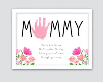 May include: A white framed print with a pink handprint in the centre of the word "MUMMY". The print includes a poem that reads "You're like the sun that brightens the day. When you're not there, the light goes away."