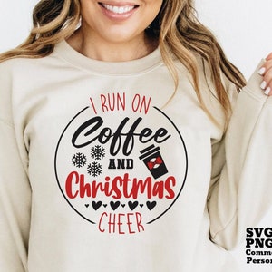 May include: A beige sweatshirt with a black and red graphic design that says "I run on coffee and Christmas cheer".