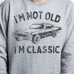 May include: Grey sweatshirt with a vintage-style graphic of a classic car and the text "I'm not old I'm classic".