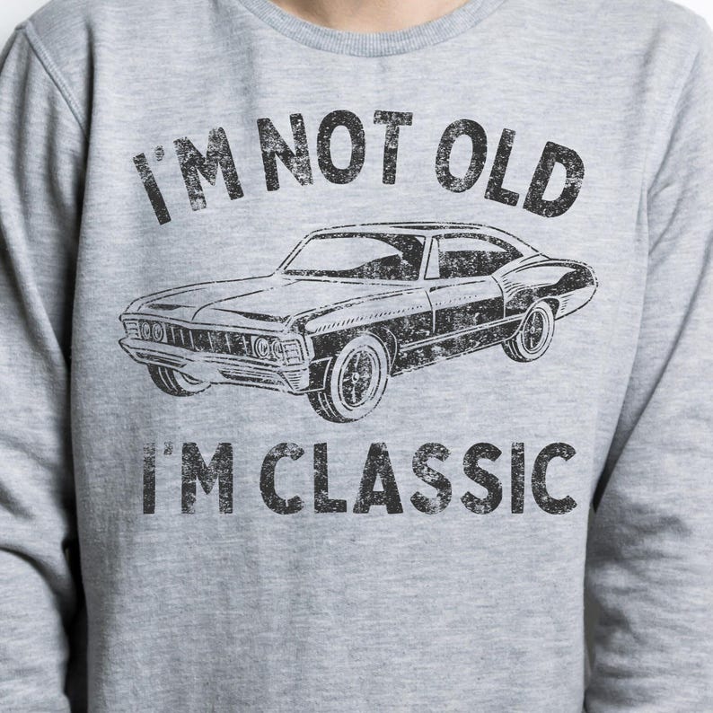 May include: Grey sweatshirt with a vintage-style graphic of a classic car and the text "I'm not old I'm classic".
