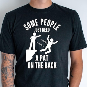 Może przedstawiać: Czarny T-shirt z białym nadrukiem przedstawiającym dwie postaci. Tekst na koszulce brzmi "Some people just need a pat on the back."