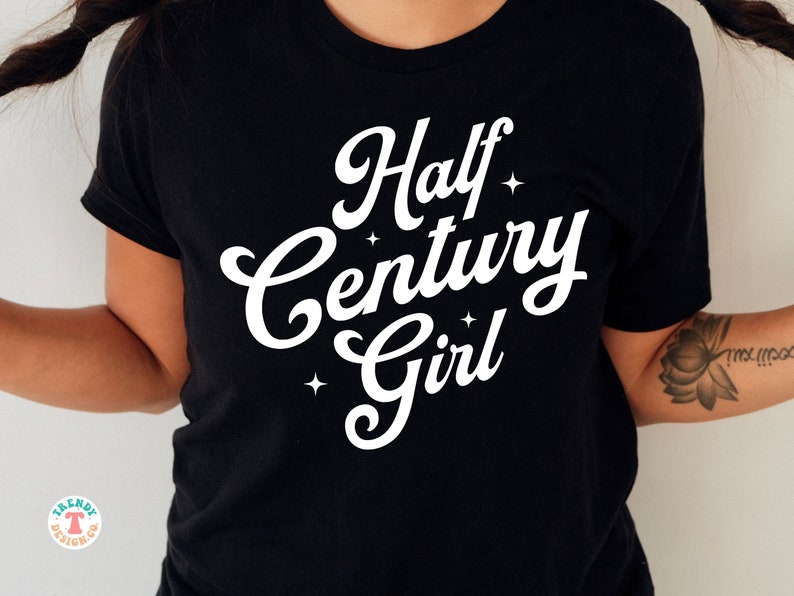 May include: Black t-shirt with white text that reads "Half Century Girl" with stars around the text.