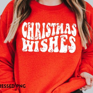 May include: Red sweatshirt with white text that reads "Christmas Wishes" in a distressed font.