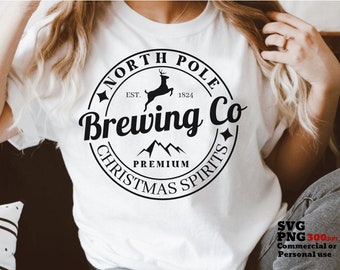 May include: White t-shirt with a black and white graphic design of a circle with the text "North Pole Brewing Co. Est. 1824 Christmas Spirits" and a silhouette of a reindeer with mountains inside the circle.