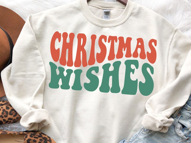 May include: A cream-colored sweatshirt with the text "Christmas Wishes" in red and green retro font.