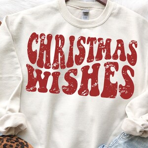 May include: A cream colored sweatshirt with a red vintage style graphic that says "Christmas Wishes".