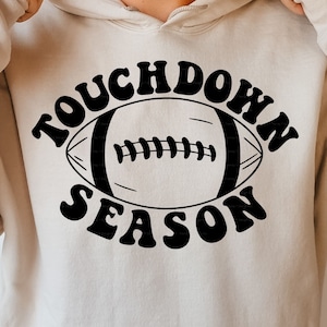 May include: A white hoodie with a black graphic design that says "Touchdown Season" with a football in the middle.