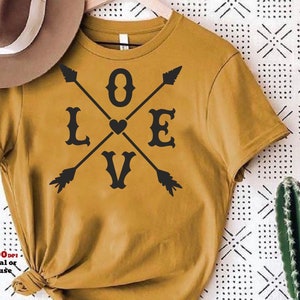 May include: A mustard yellow t-shirt with a black graphic design of crossed arrows and the word "LOVE" with a heart in the center.
