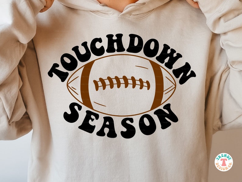 May include: A beige hoodie with the text "Touchdown Season" in black with a brown football graphic in the center.