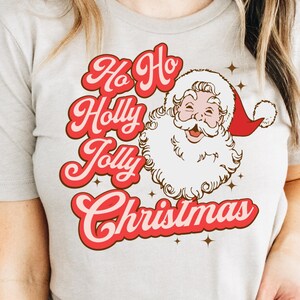 May include: A white t-shirt with a red and white graphic of Santa Claus with the text "Ho Ho Holly Jolly Christmas".