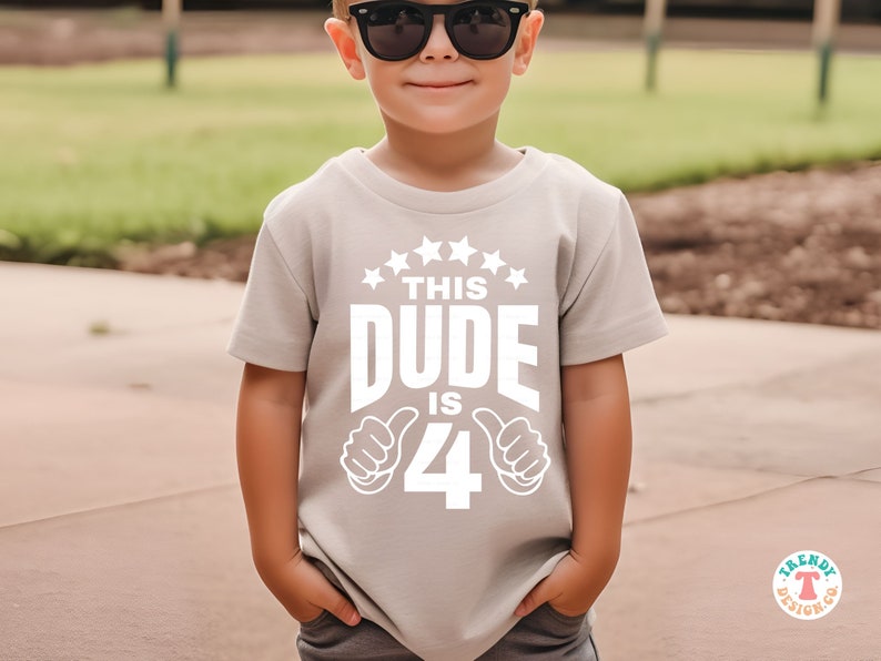 May include: A light gray t-shirt with a white graphic that says "This Dude is 4" with thumbs up on either side of the number 4.