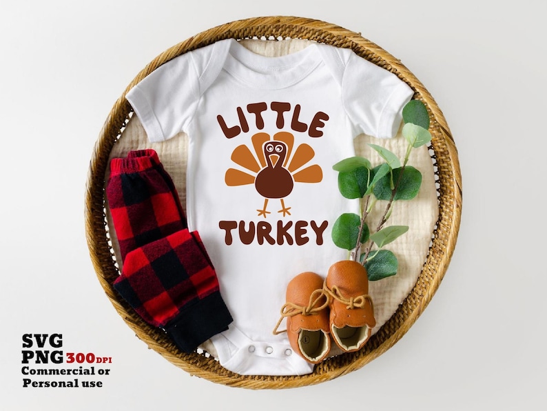Puede incluir: Un body blanco para beb&eacute; con el texto "Little Turkey" y un dibujo de un pavo de dibujos animados. El body est&aacute; en una cesta de mimbre con una tela de cuadros rojos y negros y botines marrones.