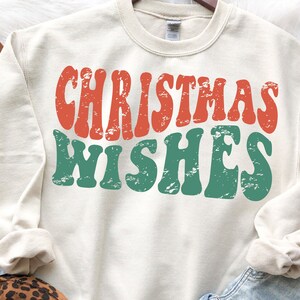 May include: A cream colored sweatshirt with the text "Christmas Wishes" in red and green retro font.