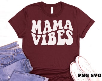 May include: A maroon t-shirt with white text that reads "Mama Vibes" in a retro font.