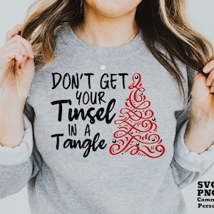May include: A gray sweatshirt with the text "Don't get your tinsel in a tangle" in black lettering and a red stylized Christmas tree design.