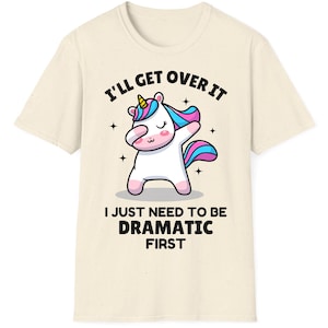 May include: A white t-shirt with a cartoon unicorn dabbing and the text "I'll get over it I just need to be dramatic first."