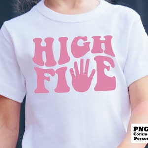 K&ouml;nnte beinhalten: Ein wei&szlig;es T-Shirt mit einer pinkfarbenen Grafik, auf der "HIGH FIVE" steht, mit einem pinkfarbenen Handabdruck in der Mitte des Wortes "FIVE".