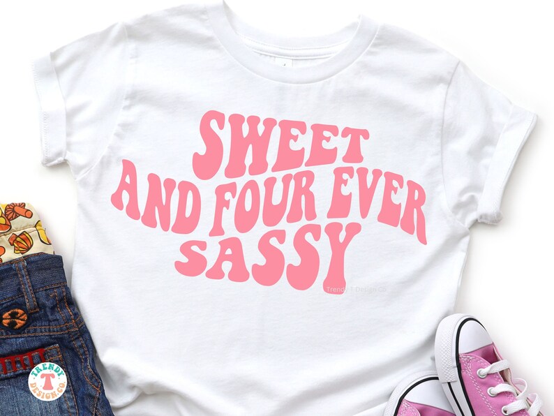 May include: White t-shirt with pink text that reads "Sweet and Four Ever Sassy" in a retro font.