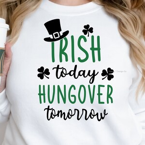 May include: White sweatshirt with black and green text that reads "Irish today, hangover tomorrow". A shamrock graphic is on either side of the text. A black leprechaun hat is above the text.