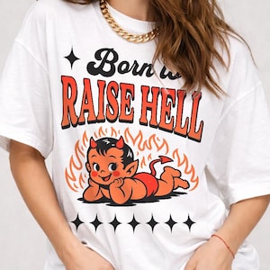 Może przedstawiać: Biała koszulka z napisem "Born to Raise Hell" w kolorze czarnym i pomarańczowym. Koszulka posiada grafikę z kreskówkowym diabłem w kolorze pomarańczowym i czerwonym, otoczonym płomieniami. Koszulka jest połączona z czarnymi szortami.