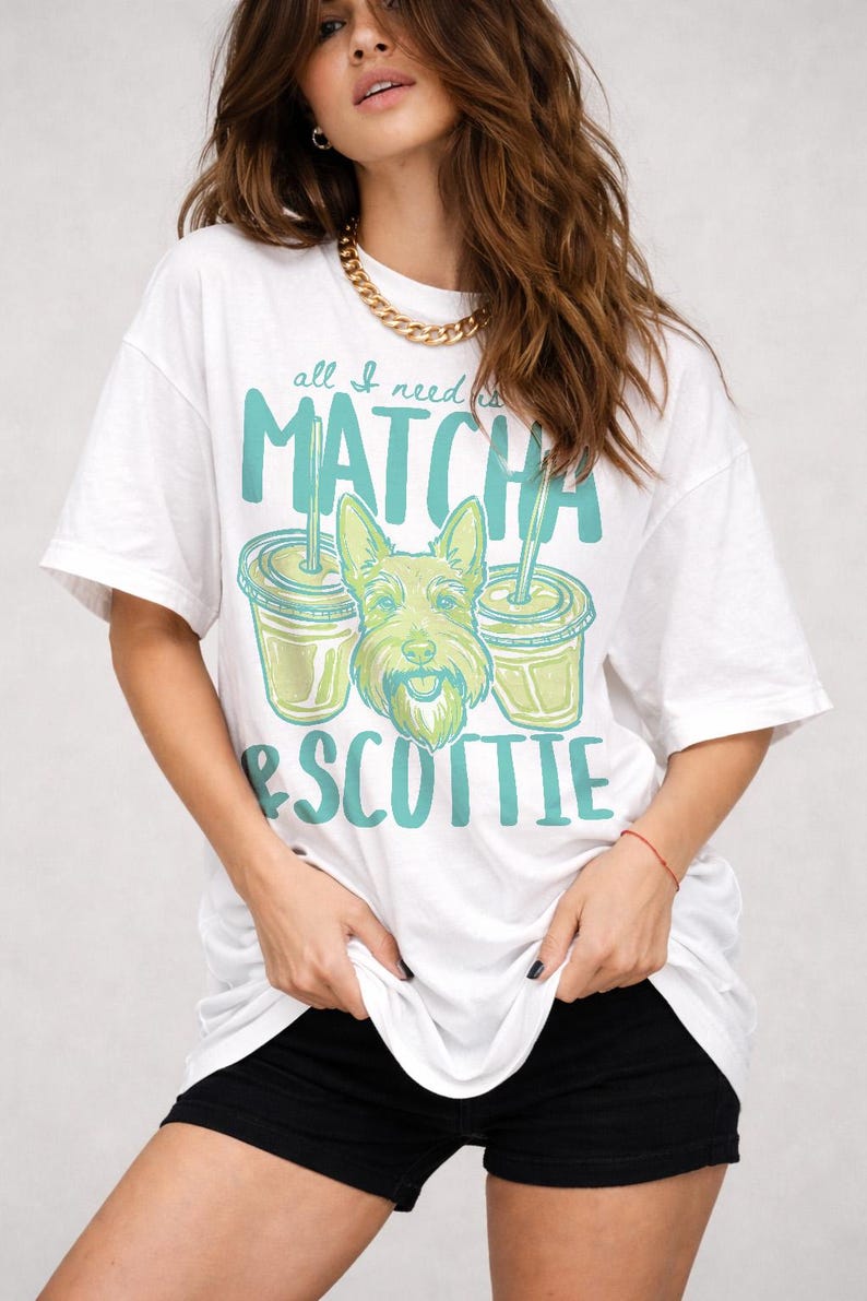 May include: White t-shirt with a graphic design featuring the text "all I need is MATCHA & SCOTTIE". The design includes two matcha drinks and a cartoon Scottish Terrier dog. The shirt is a relaxed fit.