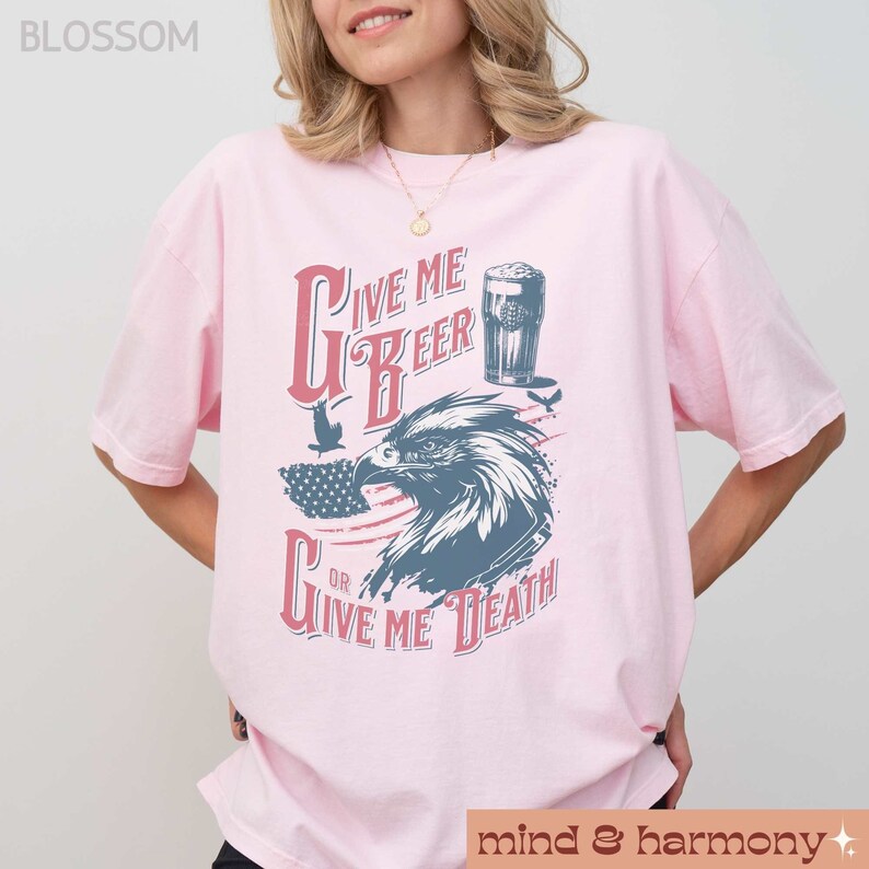 Peut inclure: T-shirt rose avec un motif graphique repr&eacute;sentant un aigle, un drapeau am&eacute;ricain et le texte "Give Me Beer or Give Me Death".