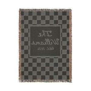 May include: A woven throw blanket with a gray and black checkerboard pattern. The center features a darker gray rectangle with the name "The Williams" and "Est. 2020" in a cursive font. The blanket has fringed edges.