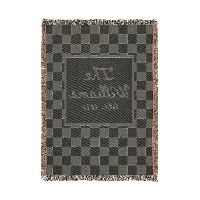 May include: A woven throw blanket with a gray and black checkerboard pattern. The center features a darker gray rectangle with the name "The Williams" and "Est. 2020" in a cursive font. The blanket has fringed edges.