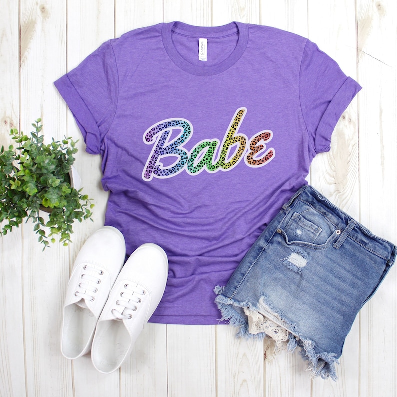 May include: Purple t-shirt with a rainbow leopard print "Babe" graphic.