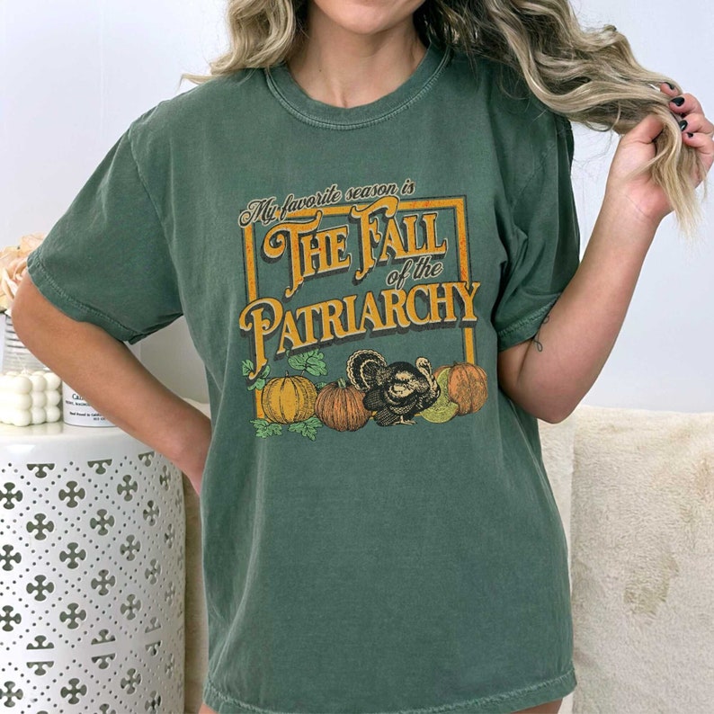 May include: A green t-shirt with a vintage-style graphic that says "My favourite season is The Fall of the Patriarchy". The graphic features a turkey and pumpkins.