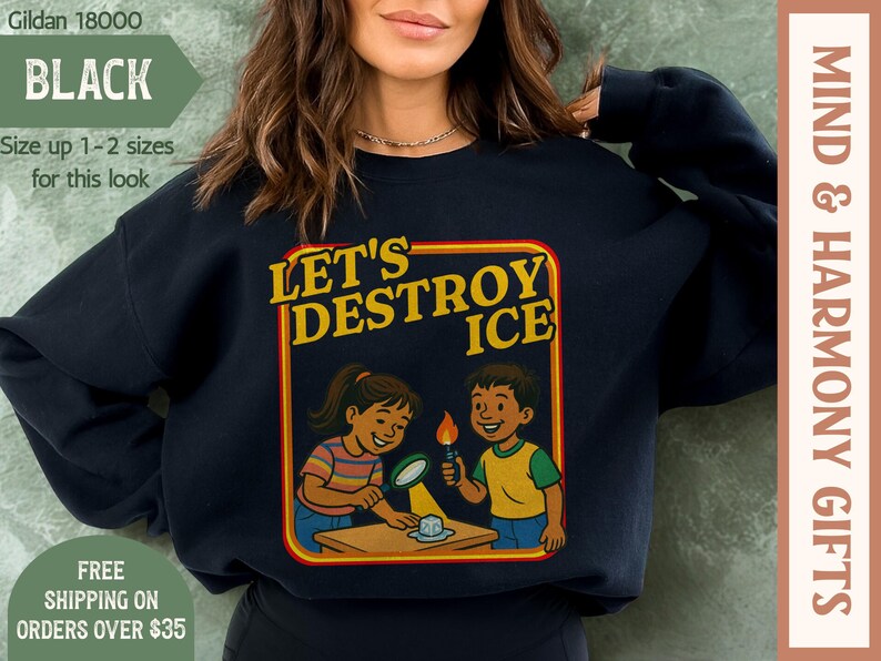 May include: Black sweatshirt with the text "LET'S DESTROY ICE" in a yellow and red frame. The graphic shows two cartoon children experimenting with ice. The sweatshirt also has the text "MIND & HARMONY GIFTS".