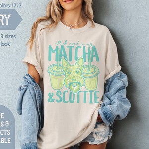 May include: Ivory-colored t-shirt with the text "all I need is my MATCHA & SCOTTIE" in teal. The graphic includes a cartoon Scottie dog and two matcha drinks. The shirt is part of the Comfort Colors 1717 collection.