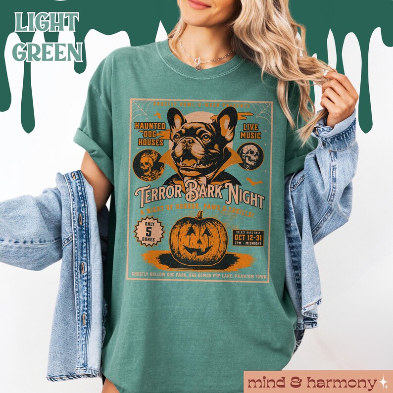 Puede incluir: Una camiseta verde azulada con un gr&aacute;fico de estilo vintage de un bulldog franc&eacute;s vestido de vampiro. El gr&aacute;fico dice "Terror Bark Night" e incluye una calabaza, casas de perros embrujadas y m&uacute;sica en vivo.