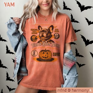 Puede incluir: Una camiseta naranja quemada con un gr&aacute;fico de estilo vintage de un bulldog franc&eacute;s vestido de vampiro. El gr&aacute;fico dice "Terror Bark Night" y presenta una calabaza con una cara de jack-o'-lantern. El texto tambi&eacute;n dice "Haunted Dog Houses" y "Live Music".