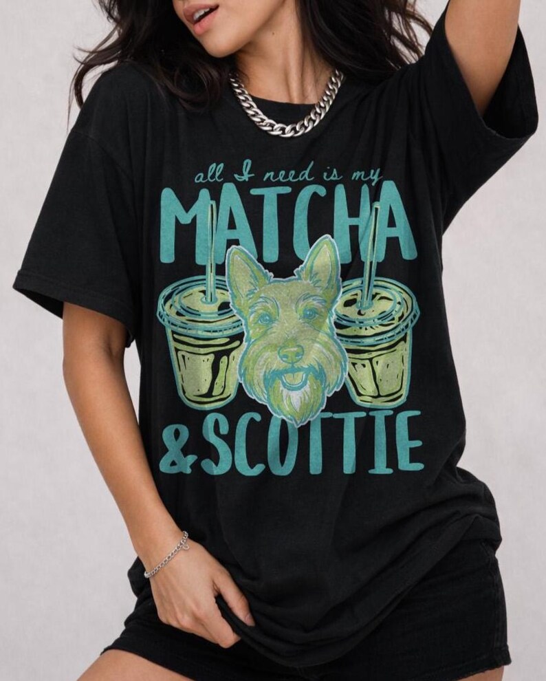 May include: Black t-shirt with the text "all I need is my MATCHA & SCOTTIE." The graphic features two matcha drinks and a green dog face. The shirt is a casual style.