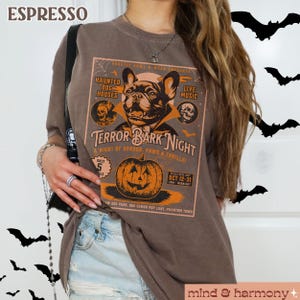 Puede incluir: Una camiseta marr&oacute;n con un gr&aacute;fico de estilo vintage de un bulldog franc&eacute;s vestido de vampiro. El gr&aacute;fico dice "Terror Bark Night: A Night of Horror, Paws & Thrills!" con detalles sobre el evento, incluyendo la fecha, la hora y la ubicaci&oacute;n.
