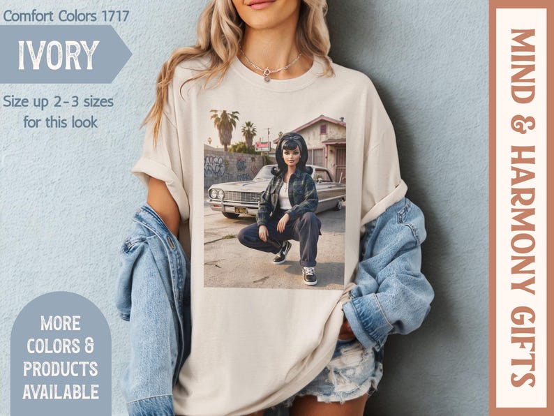 May include: Ivory Comfort Colors t-shirt featuring a graphic of a person in front of a car. The shirt has the text "Size up 2-3 sizes for this look". Additional text includes "More Colors & Products Available" and "Mind & Harmony Gifts".