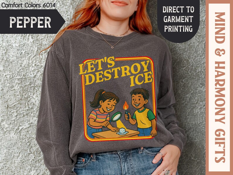 May include: Pepper-colored long-sleeve shirt with a graphic that reads "LET'S DESTROY ICE." The design features cartoon children conducting a science experiment. The shirt is made of Comfort Colors material.