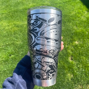 May include: A stainless steel tumbler with a black and white design of an engine. The design is detailed and intricate, featuring various engine parts.