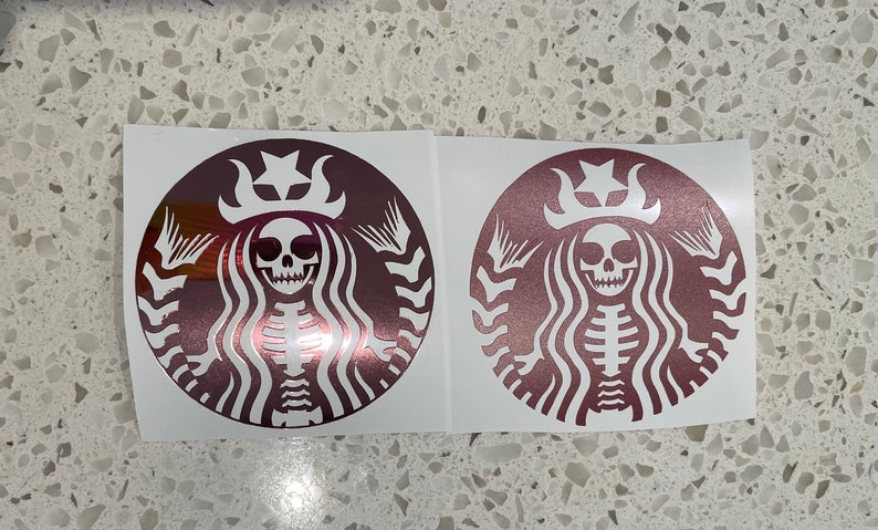 May include: Two rose gold vinyl stickers featuring a skeleton mermaid with a crown and a star on top of her head. The mermaid is in the iconic Starbucks logo shape.
